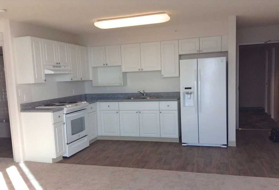 A kitchen with white appliances and cabinets.